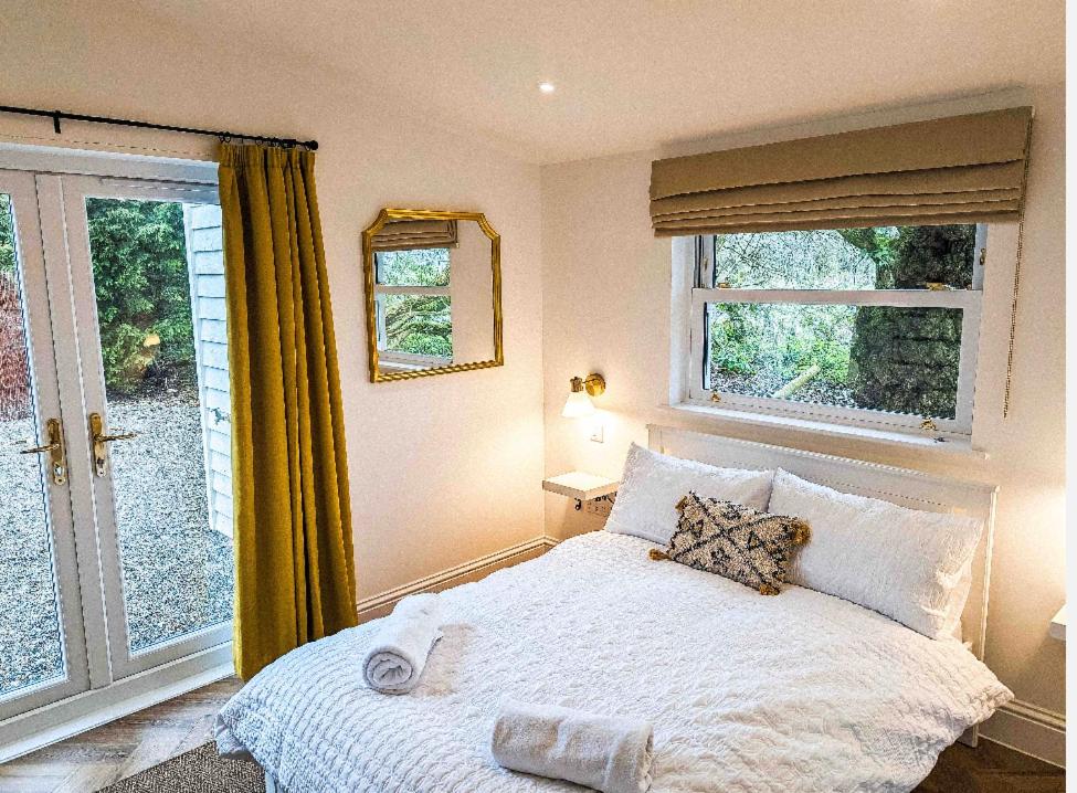 a bedroom with a white bed and a window at Palm Cottage in Kent