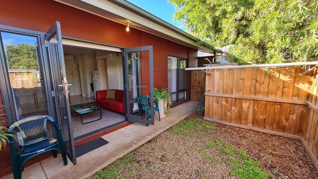 a house with a wooden fence and a red couch at Rise n' Shine - min stay 4 nights in Port Pirie