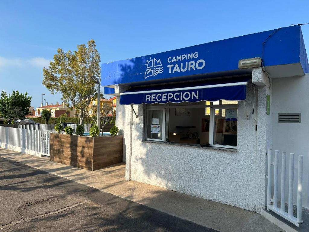 a restaurant with a blue awning on a building at Camping Tauro in Benicàssim