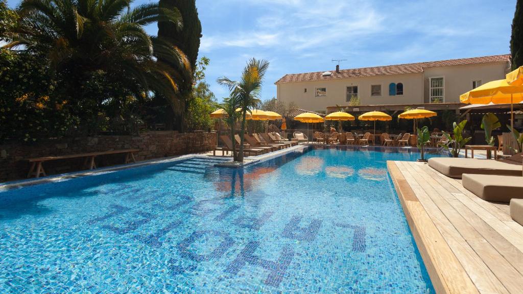 a large swimming pool with chairs and umbrellas at Hôtel La Piscine in Le Lavandou