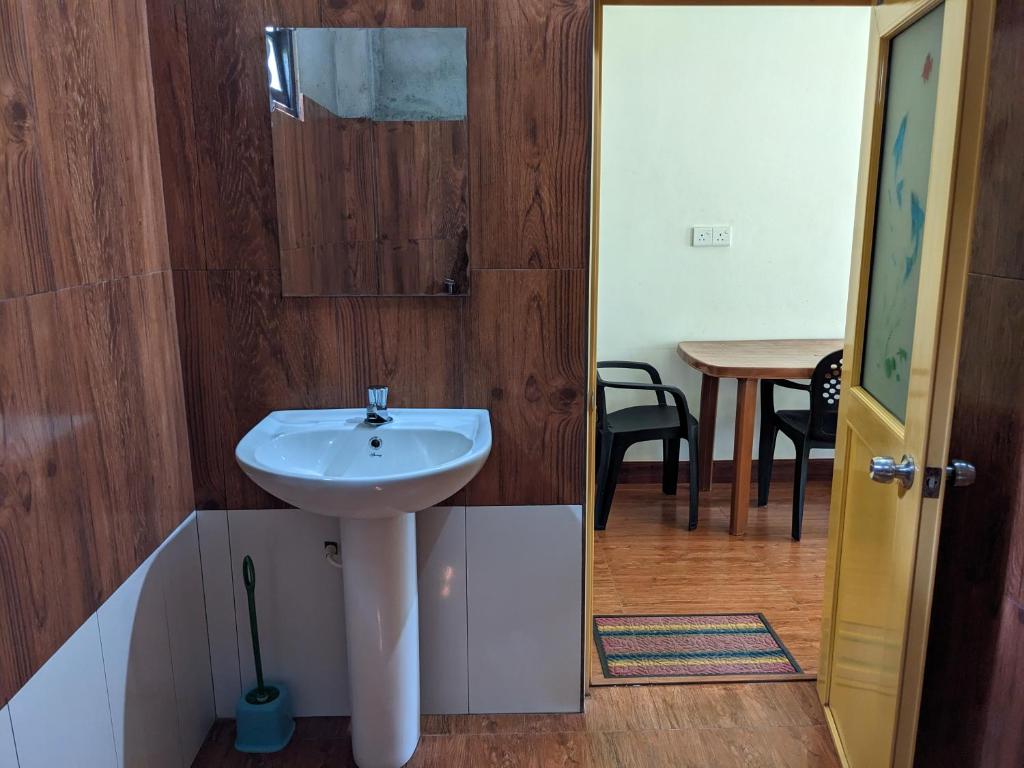 a bathroom with a white sink and a table at Afenta Hotel - Mihintale in Mihintale