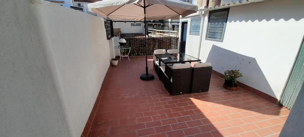 um pátio com um guarda-sol, uma mesa e cadeiras em Mediterranien Terrace em Calella