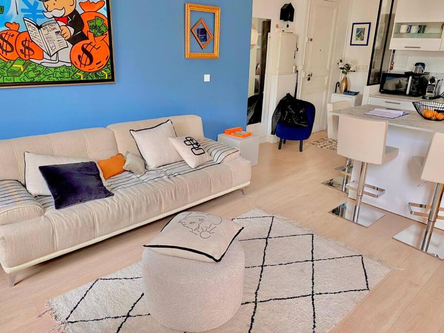 - un salon avec un canapé blanc et un mur bleu dans l'établissement Paca Properties -12CV- T2 Cosy, à Cannes
