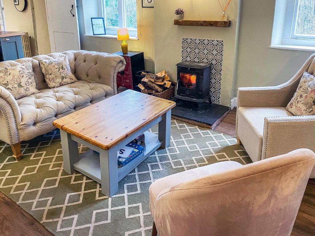 a living room with couches and a table and a fireplace at Chipley Escapes - Otters Holt in Milverton