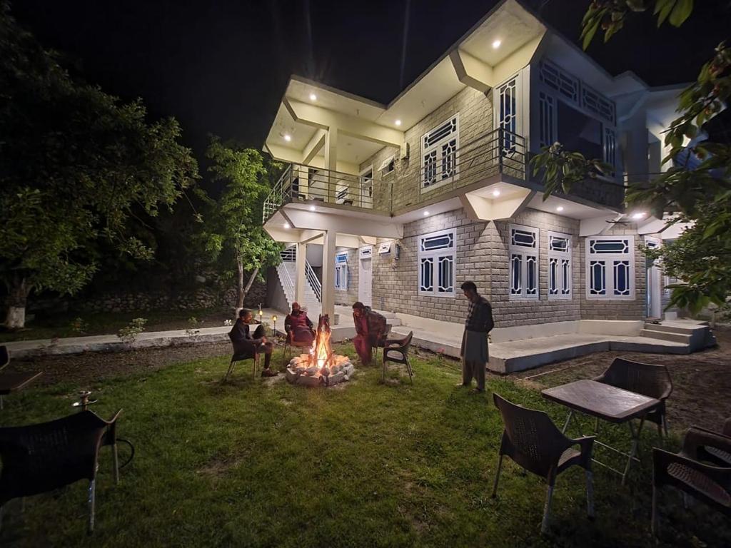 a group of people sitting around a fire in front of a house at Royal's Villa by Premiere Inn, Hunza in Hunza