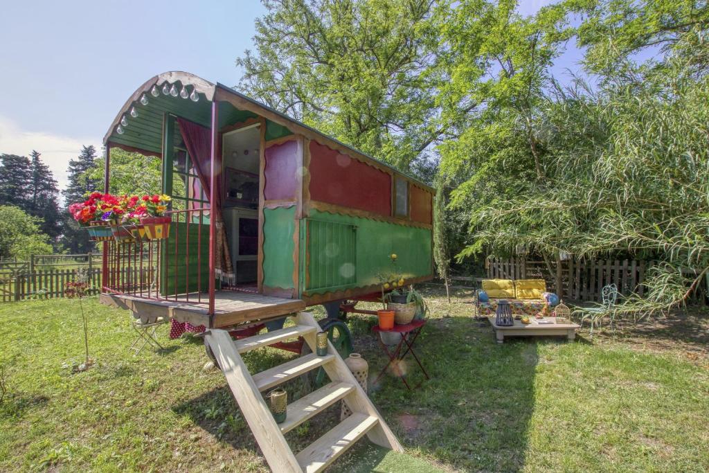 Une voiture de train verte et rouge dans une cour dans l'établissement Vent de Boheme, à Cabannes