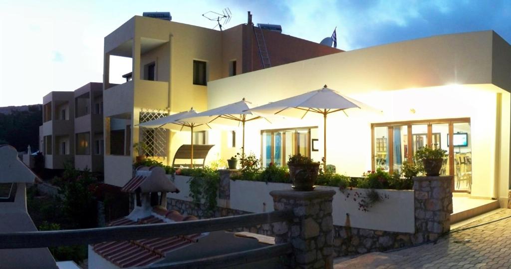 a white building with umbrellas in front of it at Miraluna Aparthotel in Lefkos Karpathou