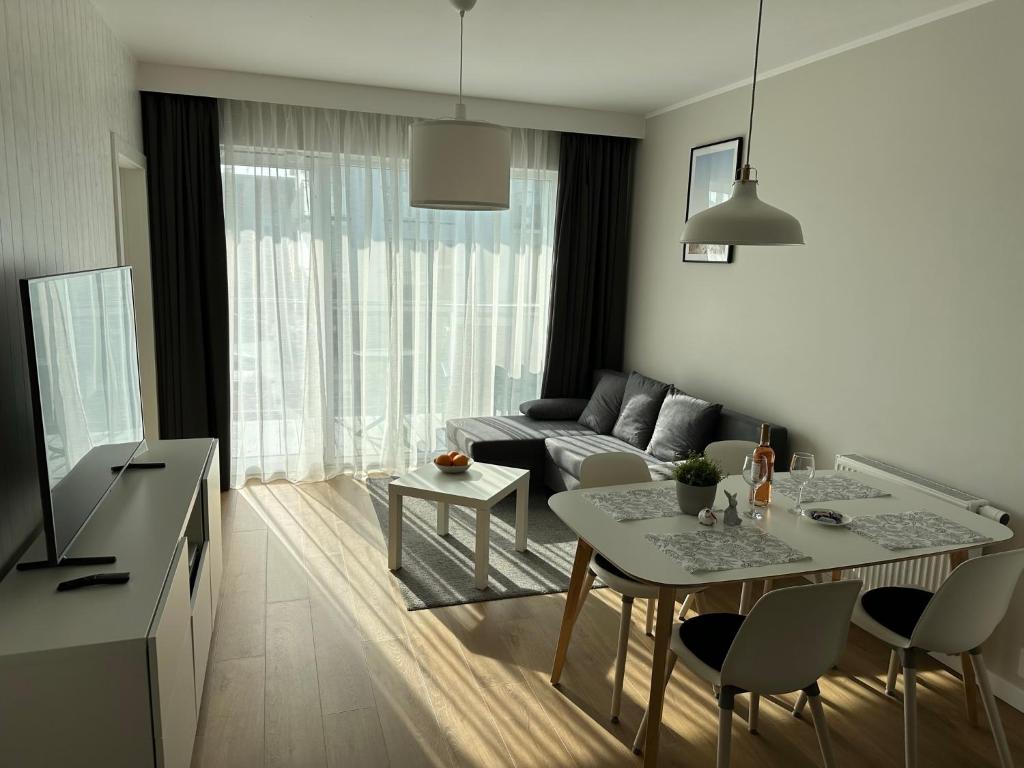 uma sala de estar com uma mesa e um sofá em Gąski Apartament Nadmorski em Gąski