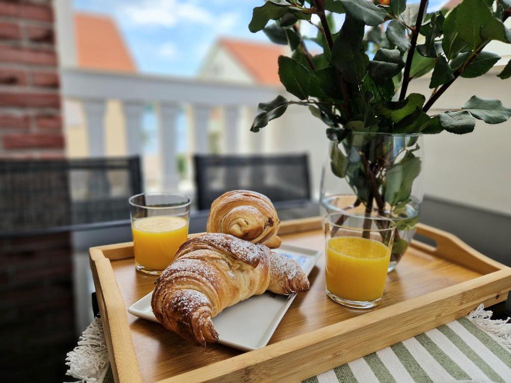 a tray with a pastry and two glasses of orange juice at Promenada Apartment in Srima