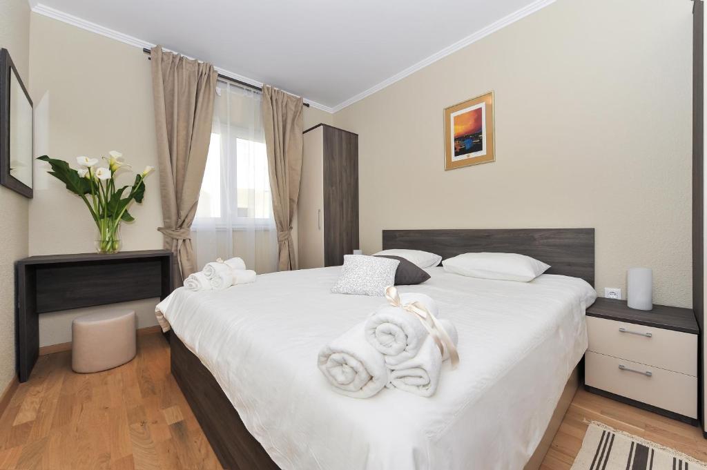 a bedroom with a large white bed with towels on it at Apartmani Perić 1 Meka Draga in Obrovac