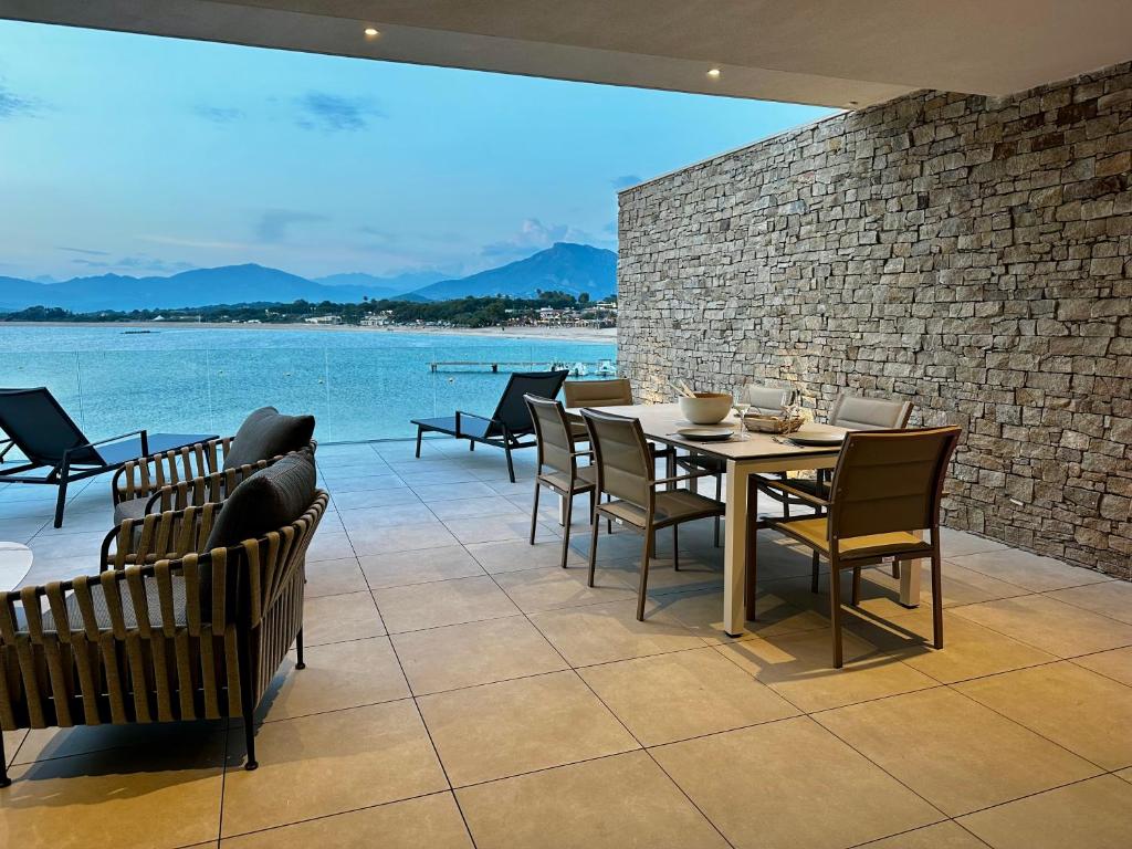 comedor con mesa, sillas y agua en RESIDENCE Neuve LE GALATEE PIED DANS L'EAU, en Porticcio