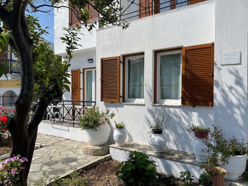 Biały dom z drewnianymi oknami i doniczkami w obiekcie Karagiozos Studios & Apartments w mieście Skopelos