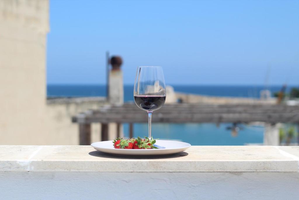 a glass of wine and a plate of food on a table at Albadamar Terrace in Trani