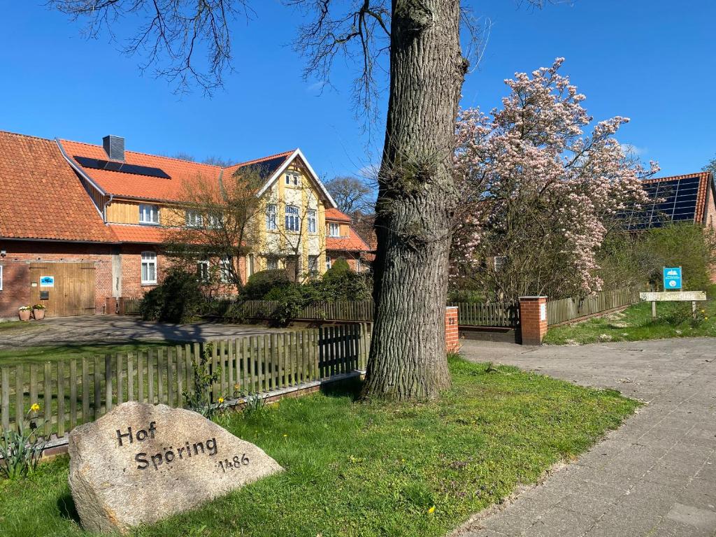 a rock sitting in the grass next to a tree at Neulandhof Spöring in Walsrode