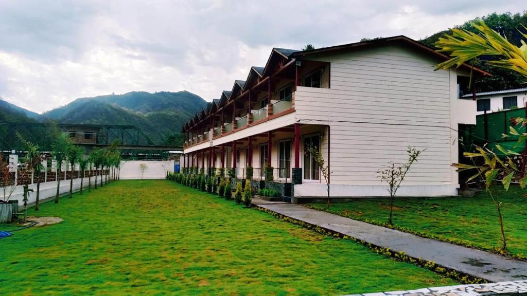 a building with a grass yard in front of it at Qcent Woods Resort & Spa, Rishikesh in Rishīkesh