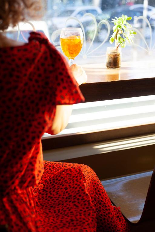a woman holding a glass of wine looking out the window at Abc Hotel in Thessaloniki