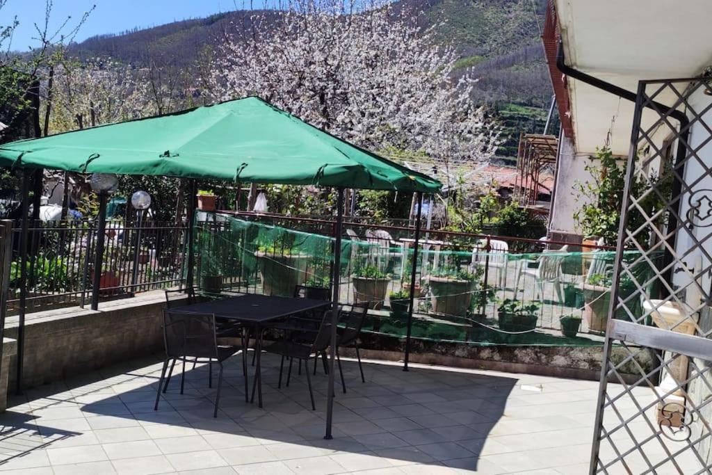 a table and chairs under a green umbrella on a balcony at casa vacanze “Tra cielo e mare” Agerola in Agerola