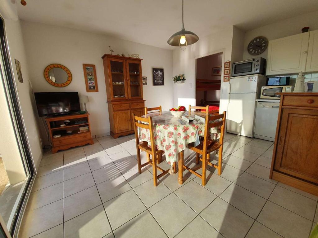 une cuisine avec une table, des chaises et un réfrigérateur dans l'établissement Appartement T2/Cabine en RDC, 4 Couchages, Terrasse, Parking Privé, à 50m de l'Océan - St-Hilaire-de-Riez - FR-1-224C-50, à Saint-Hilaire-de-Riez