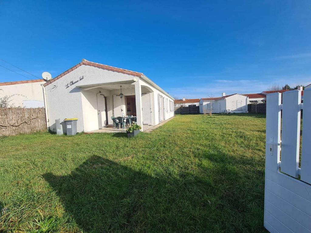 un bâtiment blanc avec une porte dans une cour dans l'établissement Maison confort proche mer avec jardin, WiFi et équipements pratiques - FR-1-224C-144, à Saint-Hilaire-de-Riez