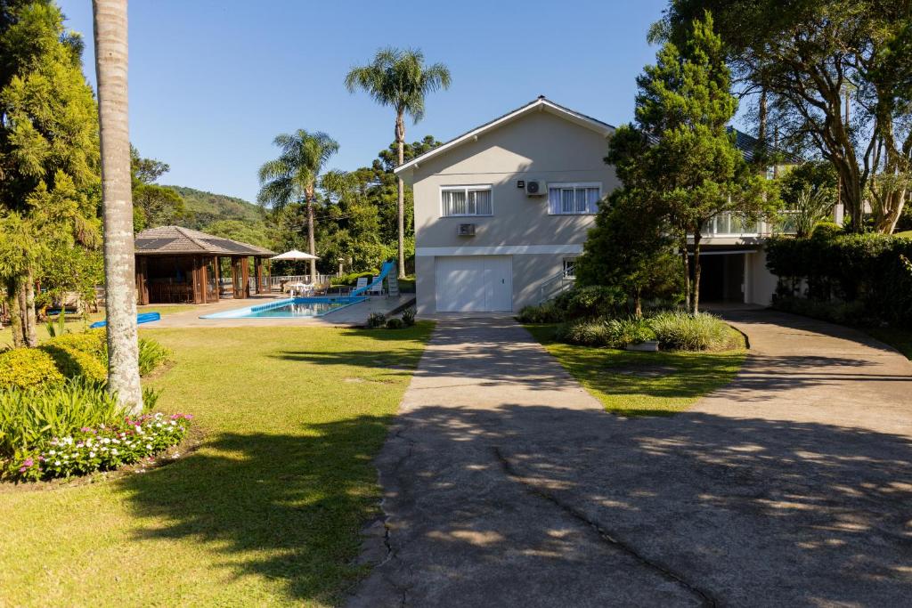 a white house with a driveway and a yard at Casa Garavaglia in Bento Gonçalves