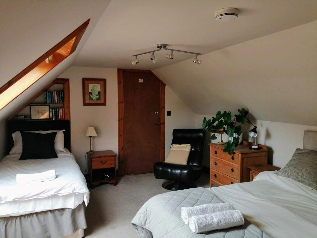 a attic bedroom with two beds and a chair at Nest Holiday Home Central Callander, Trossachs Self-catering in Callander