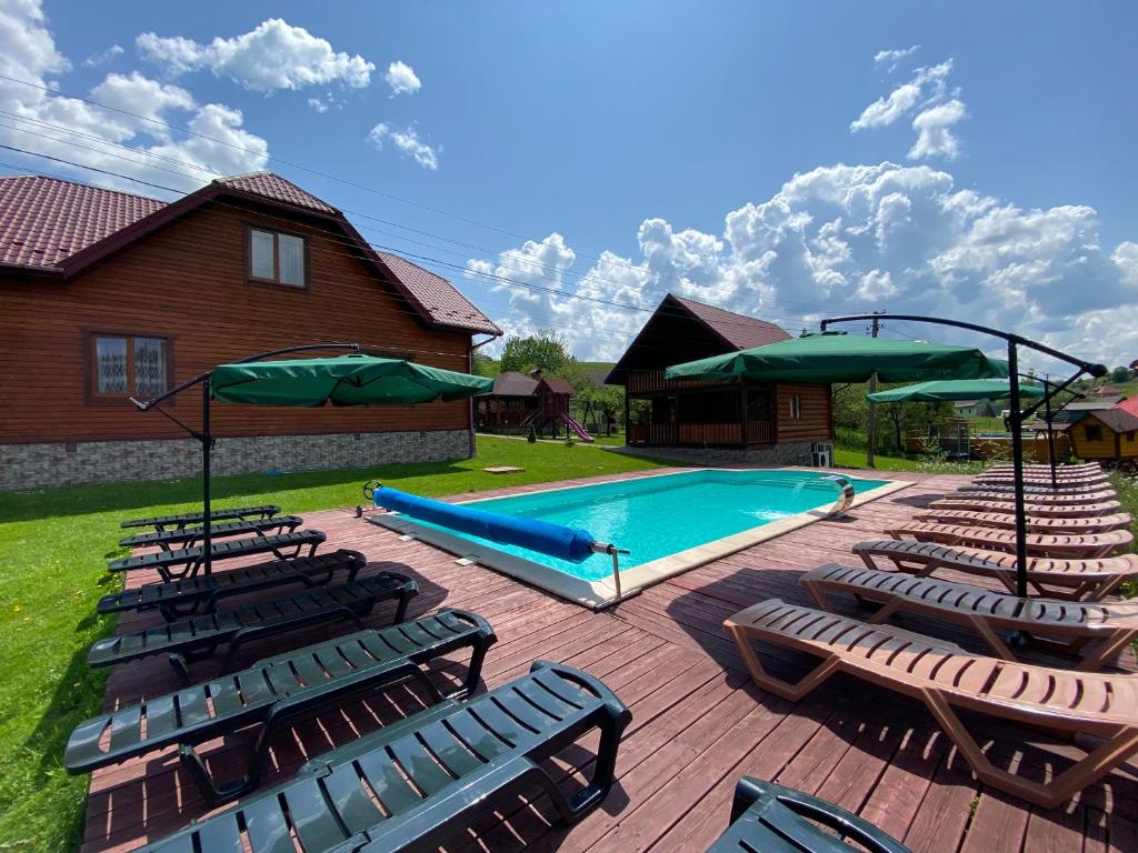 - une piscine avec des chaises longues et des parasols dans l'établissement Plavianska Sadyba, à Plavie