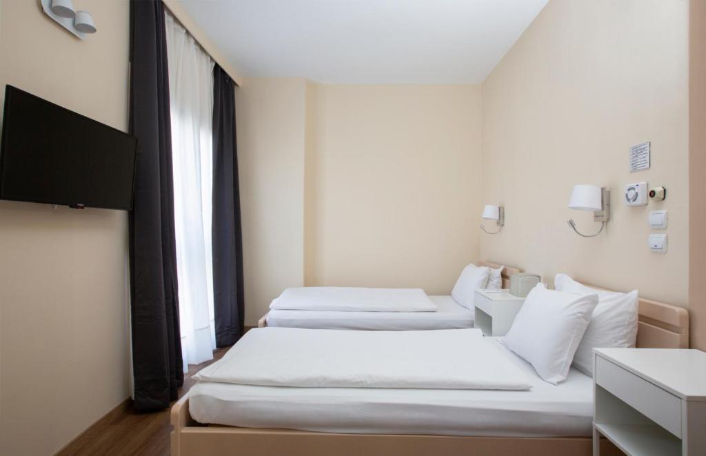 a room with three beds and a television in it at Abc Hotel in Thessaloniki