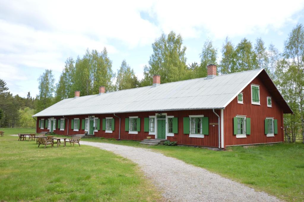a red building with picnic tables in a field at Statarlängan Hörnefors in Hörnefors