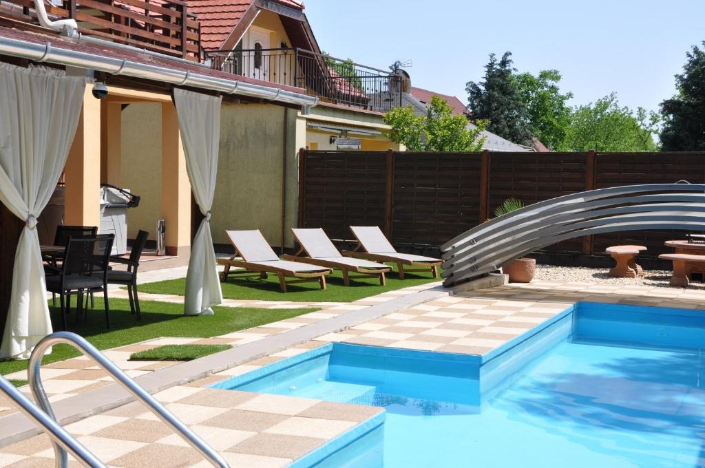 a swimming pool in a yard with chairs next to a house at Garden Villa Zsóry in Mezőkövesd