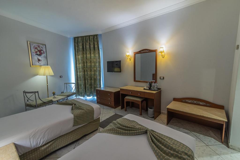 Dexon Roma Hotel في الغردقة: غرفة فندقية بسريرين ومرآة