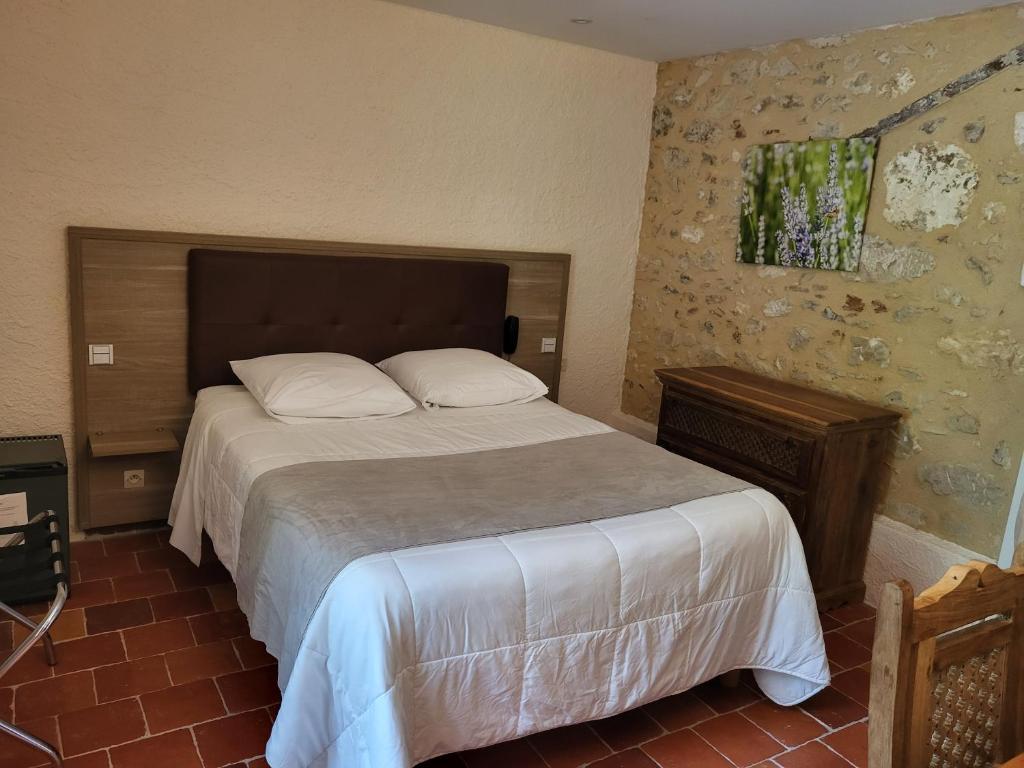 a bedroom with a large bed with white sheets at Hôtel La Flambée in Bergerac