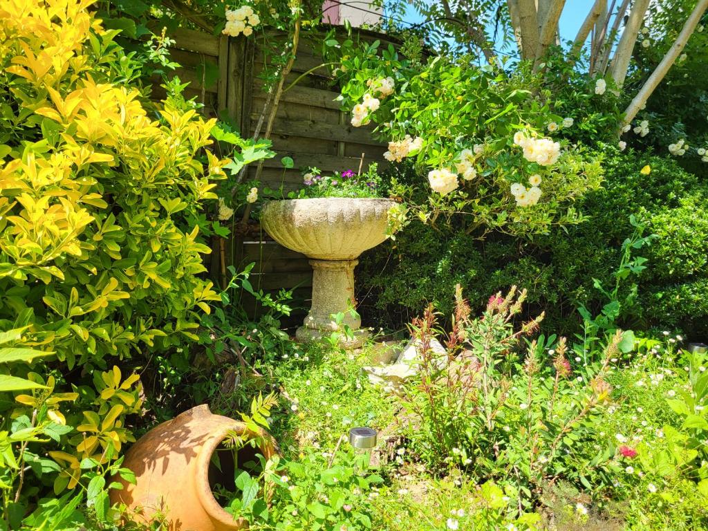 a garden with a large vase in the middle of flowers at Hôtel La Flambée in Bergerac