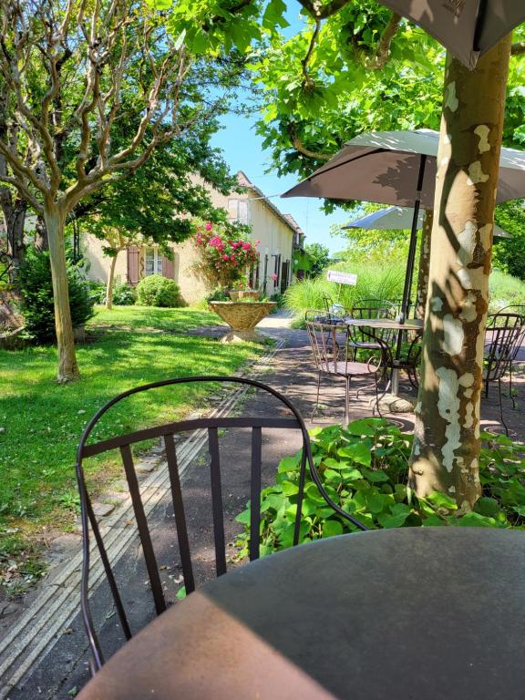 a table and chairs and an umbrella in a yard at Hôtel La Flambée in Bergerac