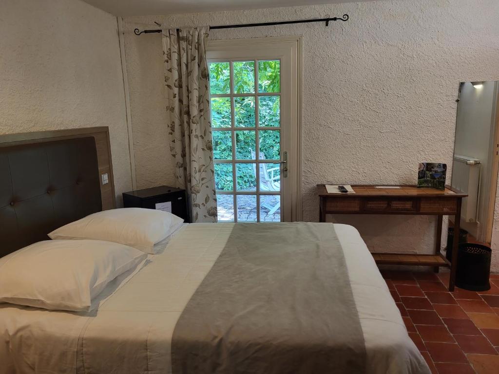 a bedroom with a large bed and a window at Hôtel La Flambée in Bergerac