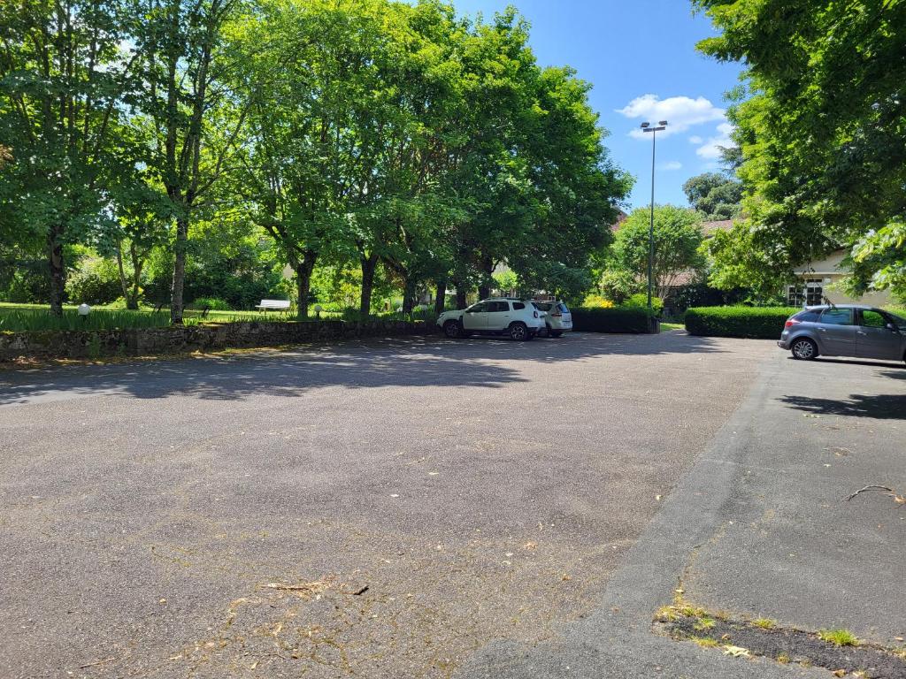 a parking lot with two cars parked in it at Hôtel La Flambée in Bergerac