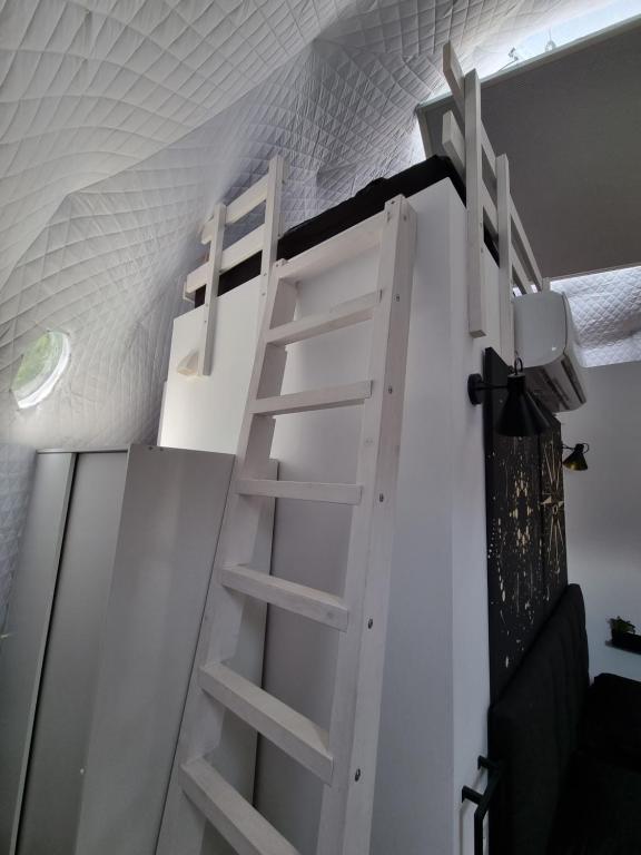 a white bunk bed with a ladder in a room at Nomad Domes in Rugineşti