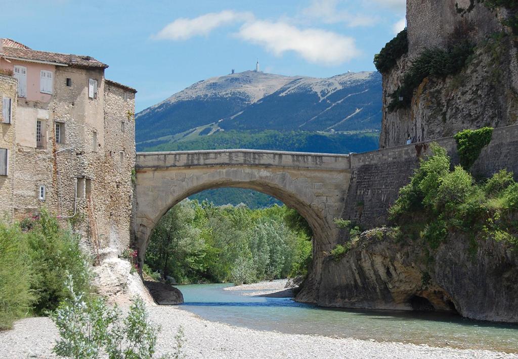 a bridge over a river with a mountain in the background at Sur le Pont in Vaison-la-Romaine