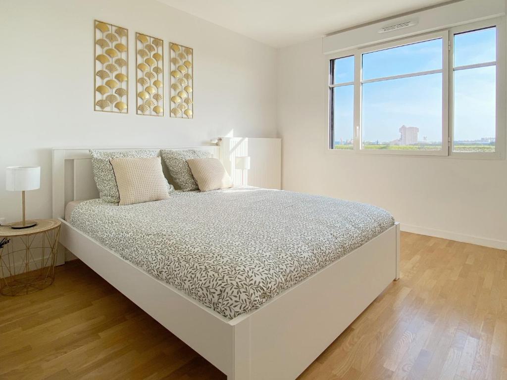 a white bedroom with a bed and a window at Suite Riviera - Vue Disneyland in Chessy