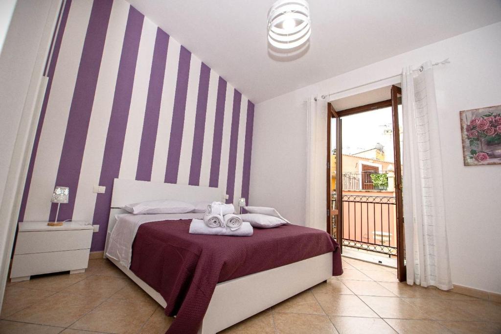 Dormitorio con cama de rayas púrpura y blanca en Quattrociocchi apartment, en Bagheria