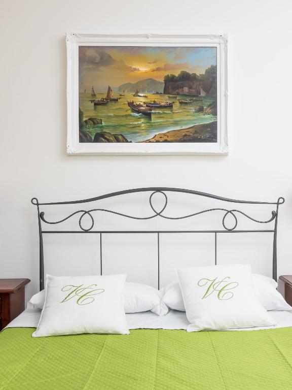 obraz nad łóżkiem z zieloną pościelą i poduszkami w obiekcie Villa Cristina - De Vivo Realty Piano di Sorrento w mieście Piano di Sorrento
