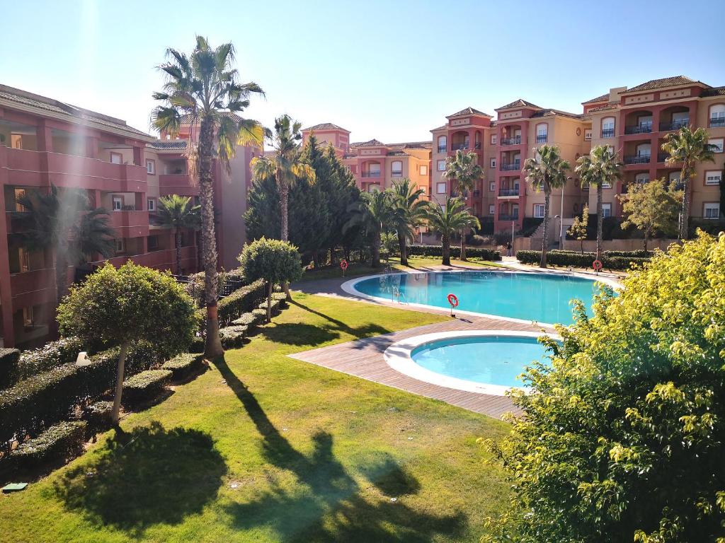 uma piscina num parque com palmeiras e edifícios em Apartamento en Resort de lujo. Golf y Playa em La Antilla
