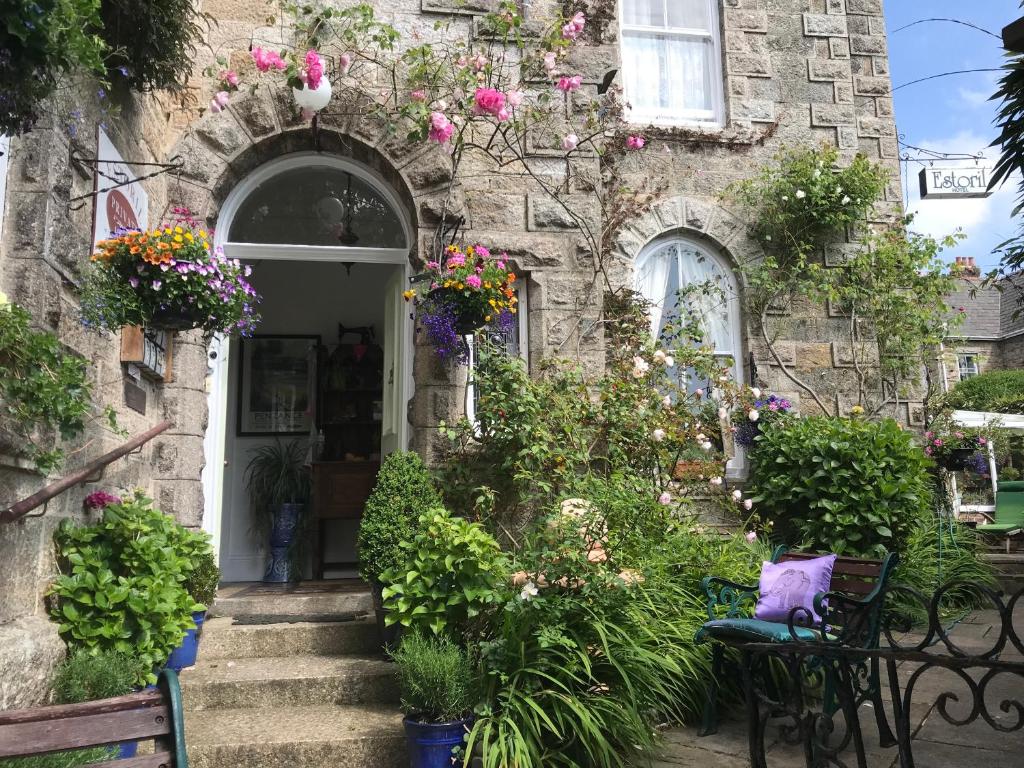 a stone house with flowers and plants in front of it at Penzance Seaside studios in Penzance