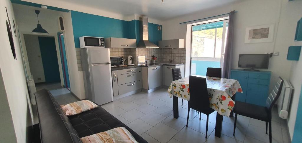une cuisine avec une table et une cuisine aux murs bleus dans l'établissement Appartement calme à quelques pas du port, à Port-Vendres