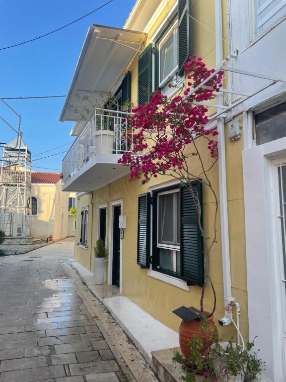 un edificio giallo con balcone e una pianta con fiori rosa di Lefkas Marine Apartment a Città di Lefkada