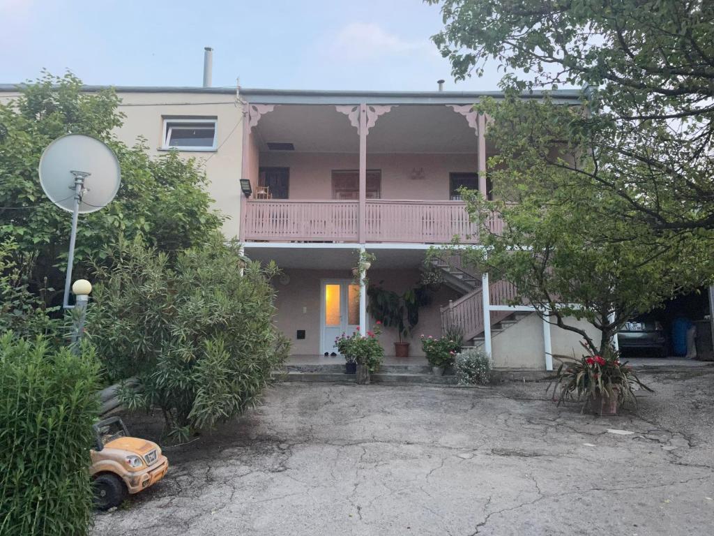 una casa rosa con balcone e una macchina parcheggiata di fronte di Kakheti Apartment a Dedoplis Tskaro