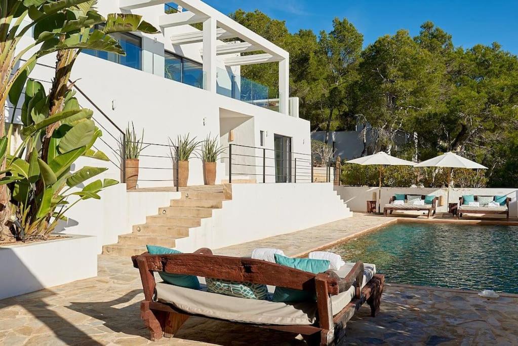 een huis met een zwembad en een houten bank bij Villa Larosa with seaview in Es Cubells Ibiza in Es Cubells