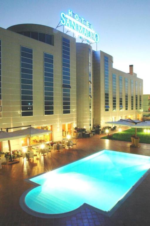 un grand bâtiment avec une piscine éclairée dans l'établissement Hotel San Mauro, à Casalnuovo di Napoli