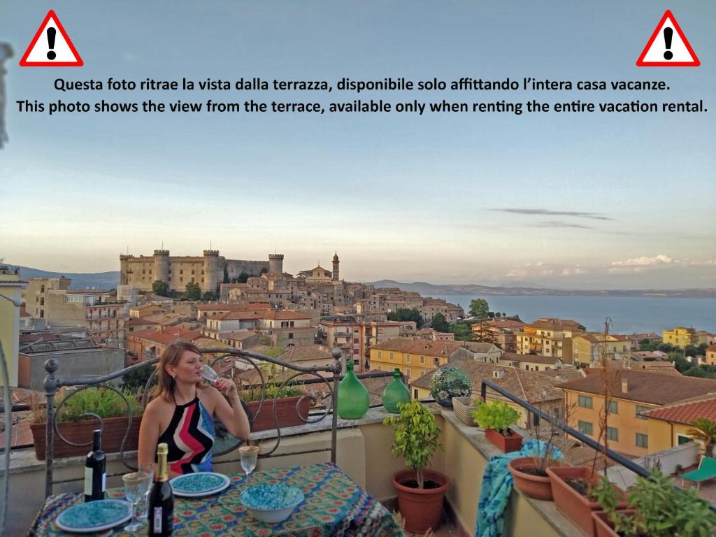 a woman sitting on a balcony with a view of a city at Il Camaleonte in Bracciano