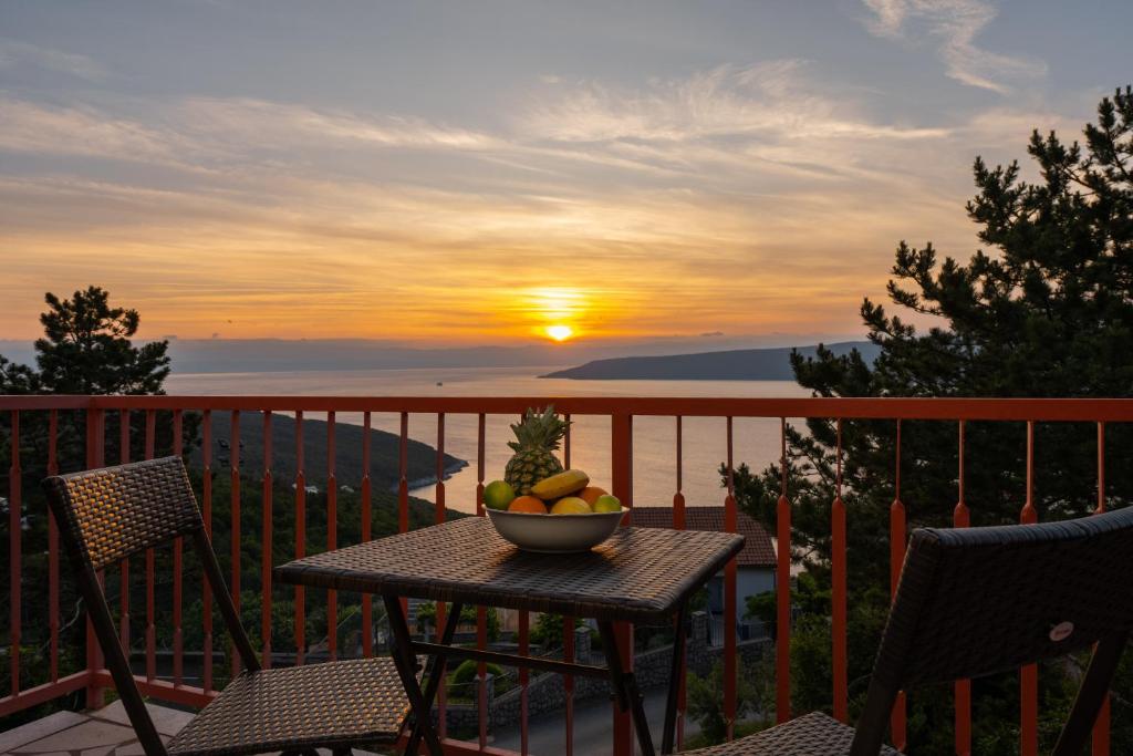 eine Schale Obst auf einem Tisch auf einem Balkon mit Sonnenuntergang in der Unterkunft Luxury Seaview Apartment in Juraši