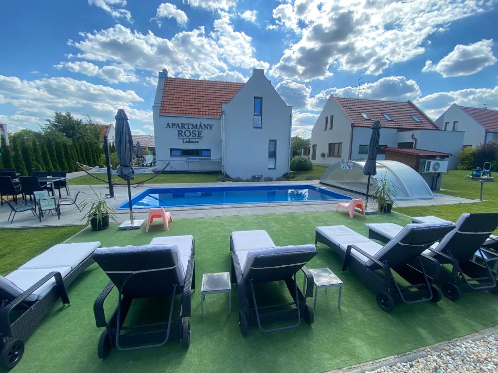 un patio trasero con piscina y sillas y una casa en Apartmány ROSE Lednice, en Lednice